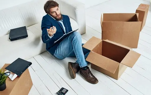 man sitting on floor unpacking while working